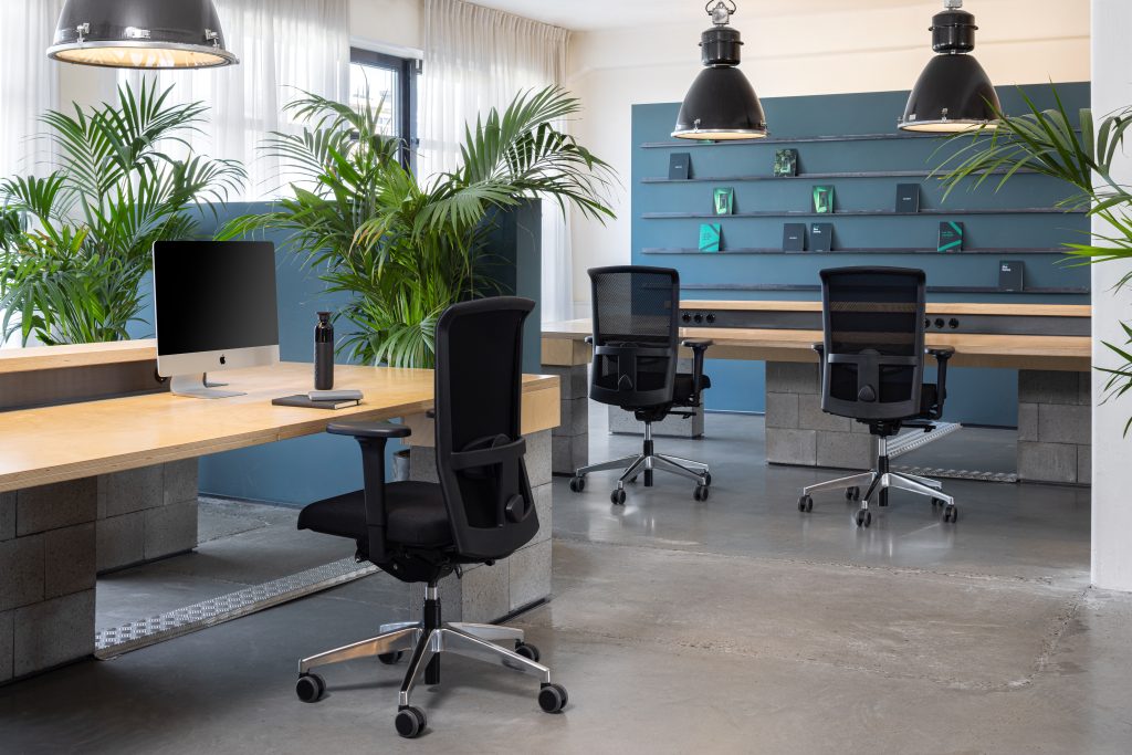 Werkplek met houten bureaus en zwarte bureaustoelen Se7en LX282.