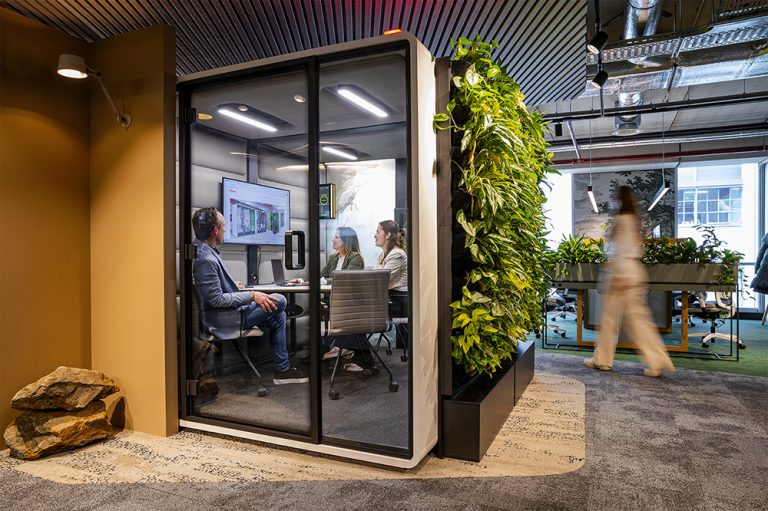 Akoestische vergadercabine met groene planten aan de buitenkant.